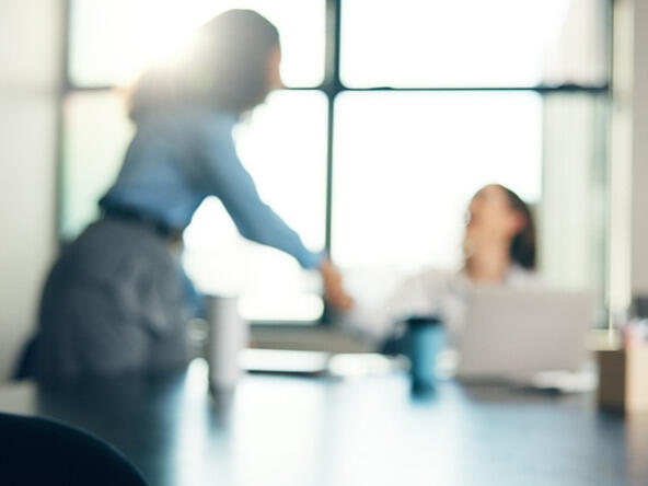 blurry people shaking hands in office